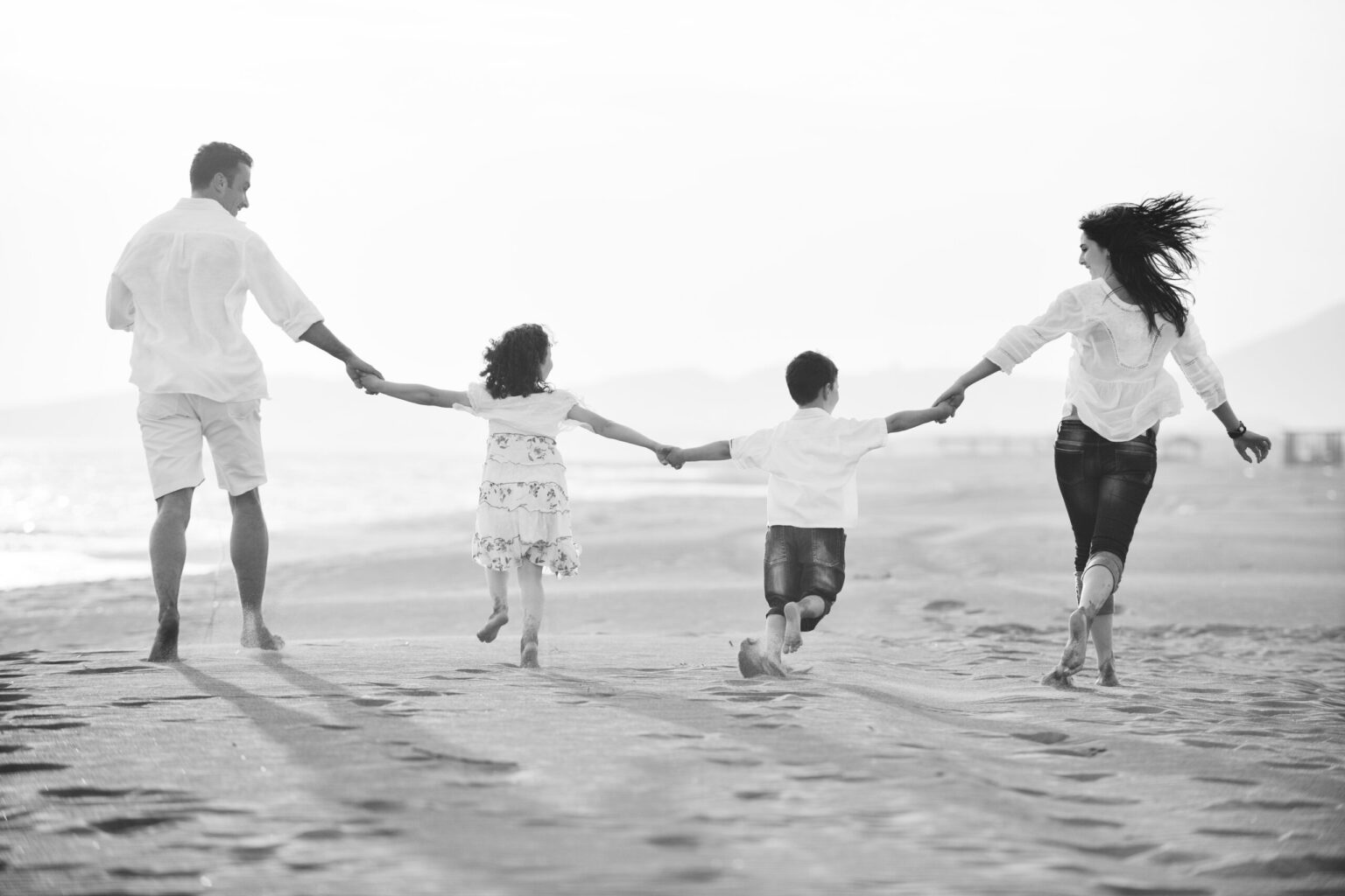 A family holding hands as they run along a beach