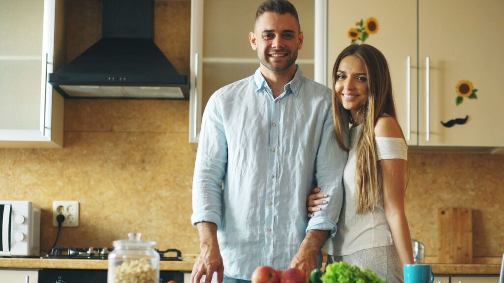 Happy couple standing together in their kitchen at home