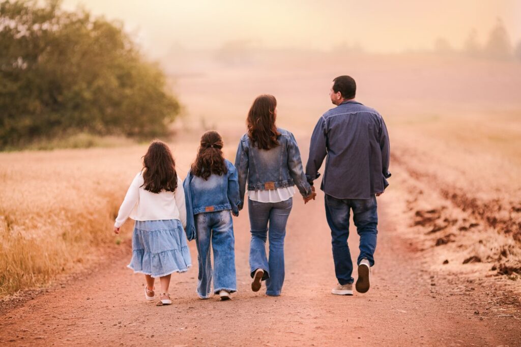 Familia caminando de la mano por un camino rural hacia el atardecer