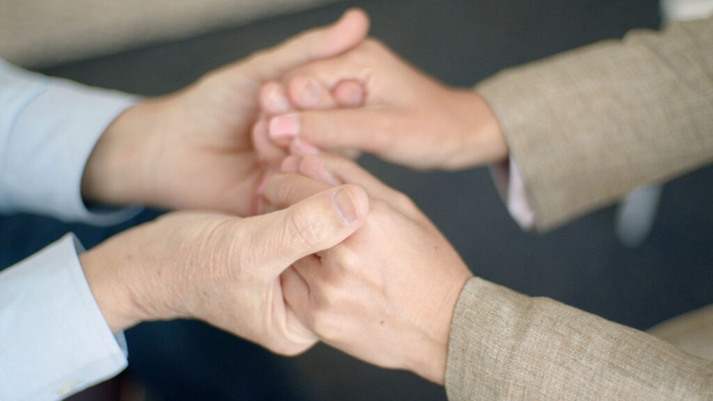Two people holding hands in a gesture of support