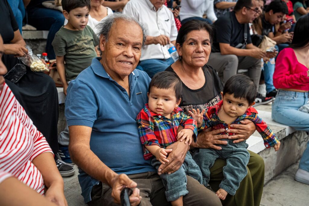 Latino grandparents smiling with their grandchildren at a family gathering