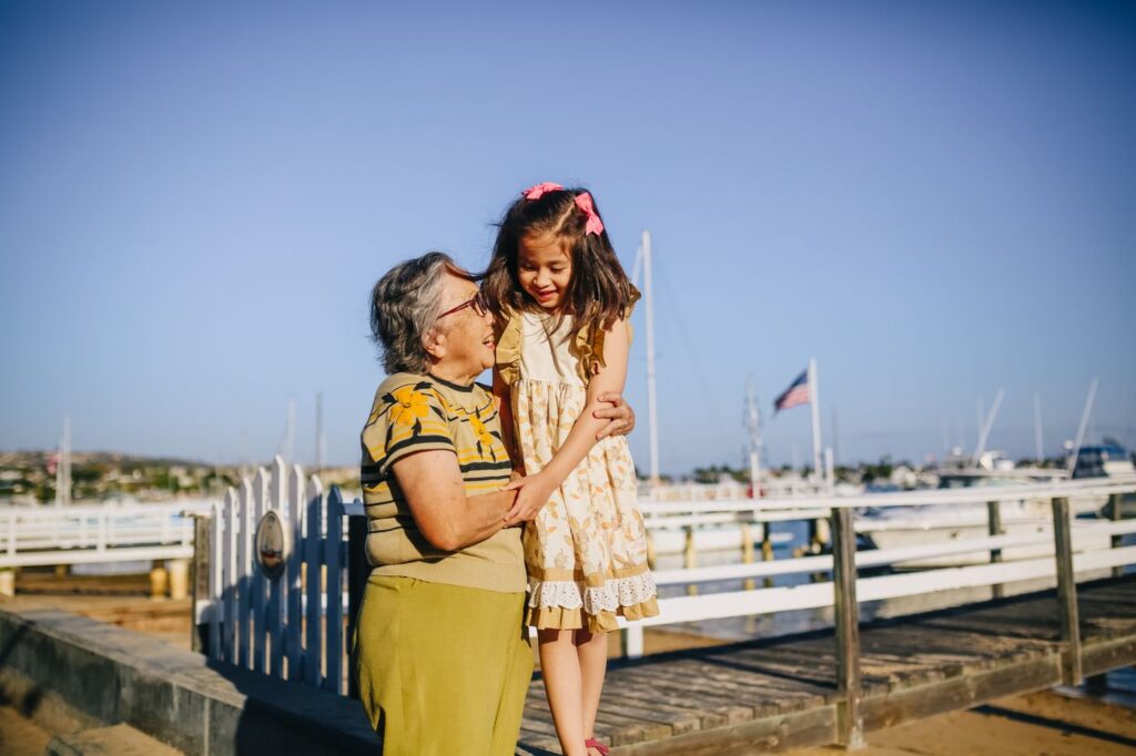 Grandmother and granddaughter hugging outdoors by the water