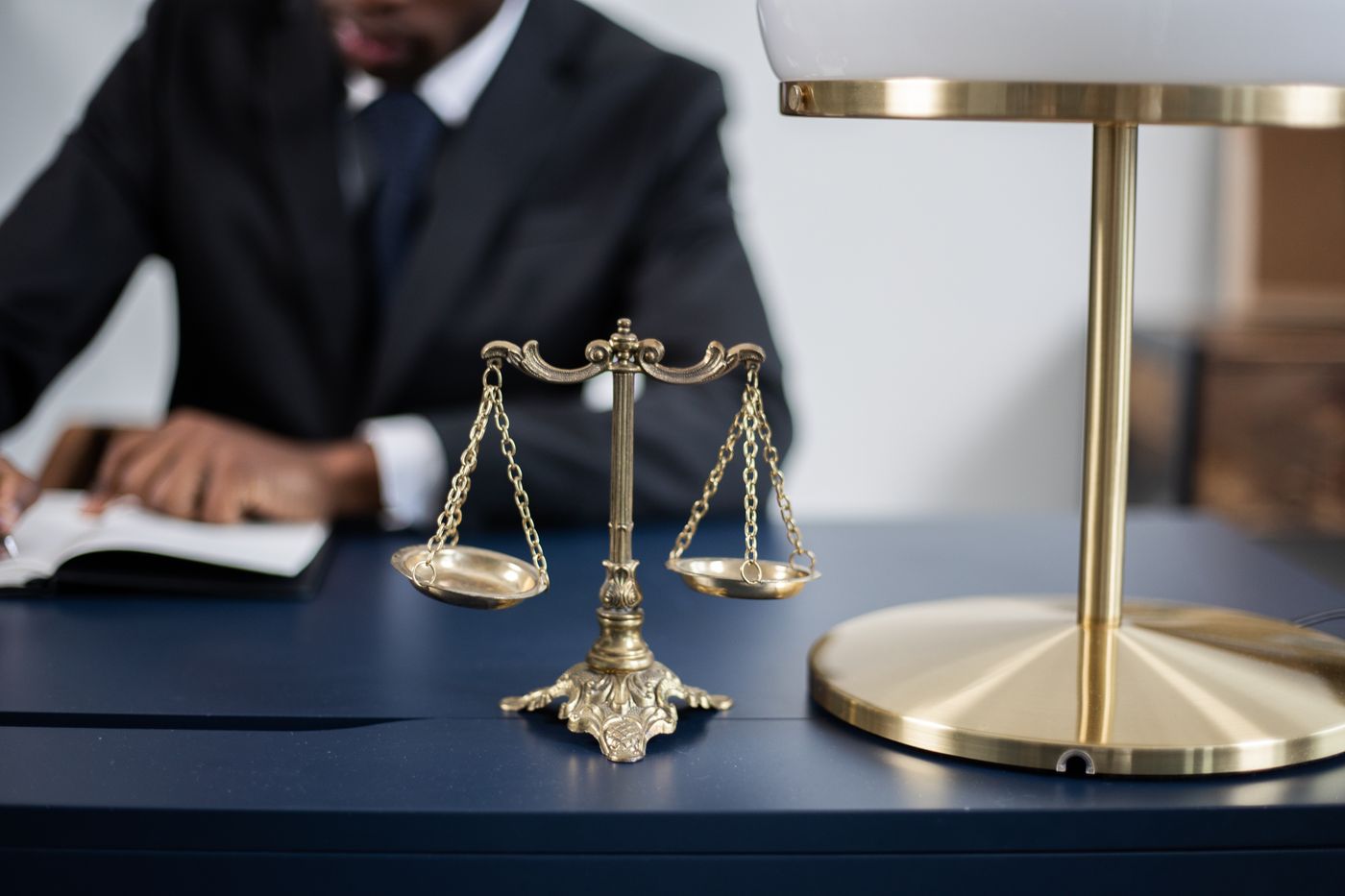 Balanza de la justicia sobre un escritorio mientras una persona trabaja