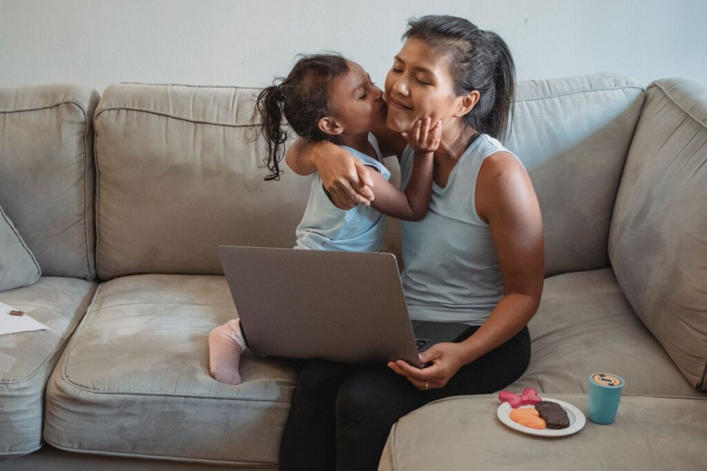 Madre e hija abrazadas y riendo en el sofá de su casa